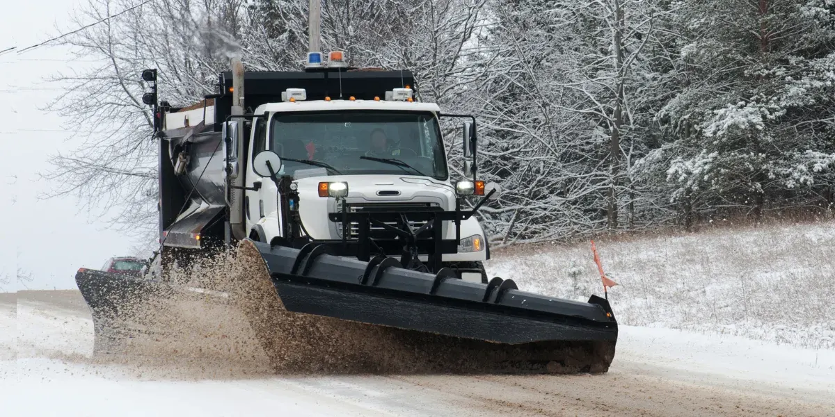 Déneigeuse en opération, lame baissée sur une route enneigée